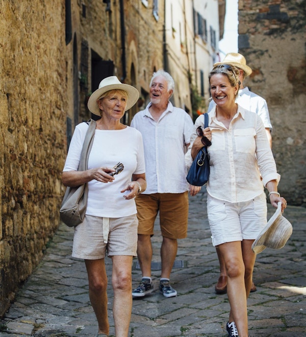 Eldre vennepar som ser seg rundt i gamlebyen i Italia. De går nedover en smal gate mens de er på ferie.