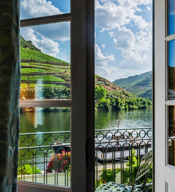Åpen verandadør med elven Douro og vinranker langs.
