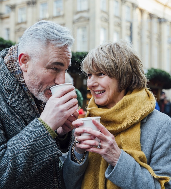 Eldre par drikker varme drikker i et julemarked i byen.