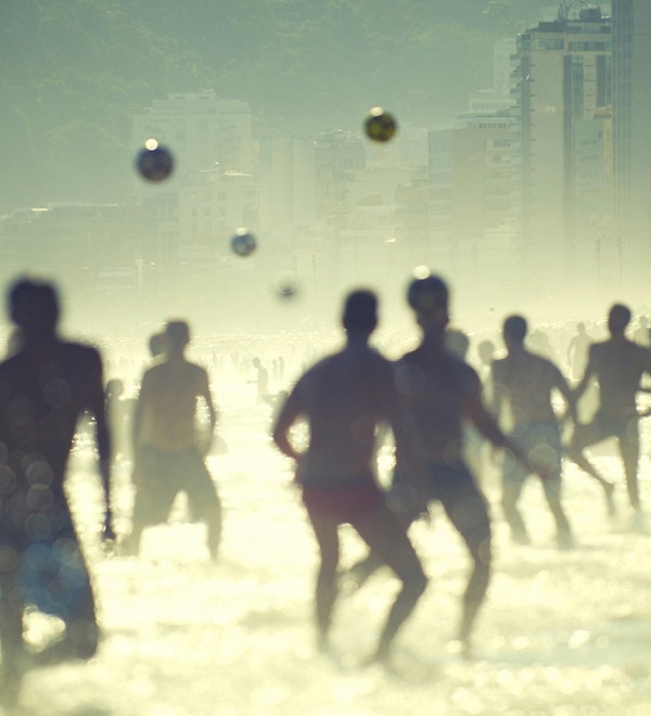 En gruppe mennesker spiller volleyball i solen på stranden