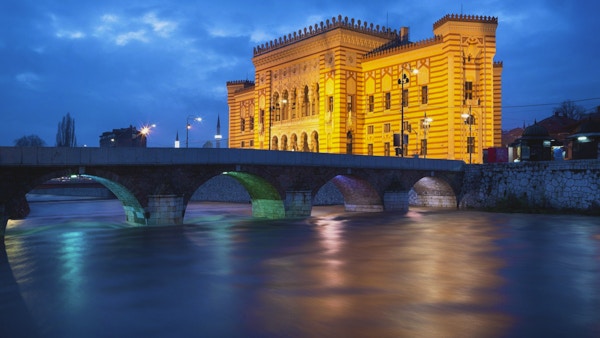 Langt eksponeringsbilde av Miljacka-elven, Seher-Cehaja-broen (bygget i 1586) og rådhuset eller nasjonalbiblioteket (bygget i 1896) i Sarajevo, Bosnia.