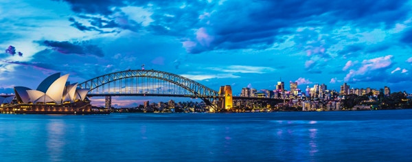 Solnedgang i Sydney med Harbour Bridge og operahuset i Sydney i bakgrunnen.
