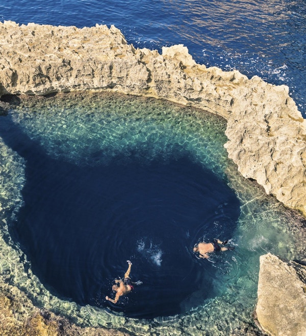 Dypblått hull ved det verdensberømte Azure Window på Gozo-øya - middelhavsunderrund på det vakre Malta - Ukjennelige turistdykkeere som svømmer til vannvannhule