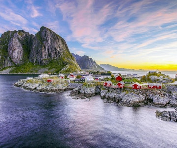 Populær utsikt over fiskehytter (rorbuer) i Hamnøy, Norge med Lilandstinden fjelltopp som bakgrunn under soloppgang