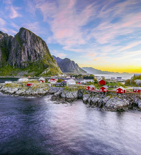 Populær utsikt over fiskehytter (rorbuer) i Hamnøy, Norge med Lilandstinden fjelltopp som bakgrunn under soloppgang