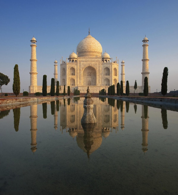 Taj Mahal lyser vakkert ved soloppgang, da den gjenspeiles i en rolig vannfontene.