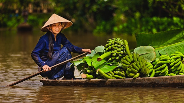 Vietnamesisk kvinne som ror en båt på Mekong elvedelta, Vietnam