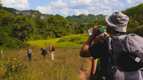 "En mann drikker fra en flaske vann under en tre-dagers fottur i landlige Myanmar, fra Kalaw til Inle Lake. Fire turgåere og deres guide er på bildet:"