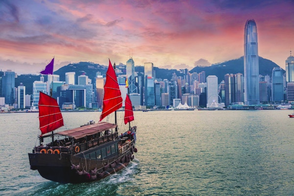 Seilbåt seiler inn til Hong Kong Victoria Harbour ved solnedgang