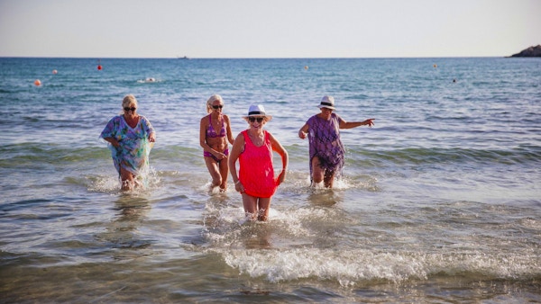 Liten gruppe eldre kvinner som morer seg i havet. Sommerdag på Kypros.