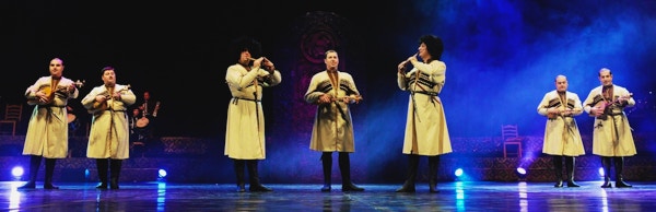 Syv musikere i nasjonaldrakter spiller og synger på en scene