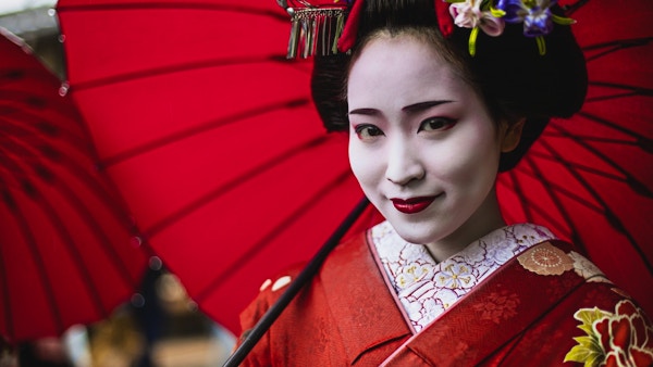 Nærbilde av geisha med rød parasoll.