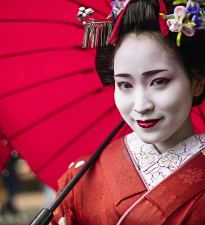 Nærbilde av geisha med rød parasoll.