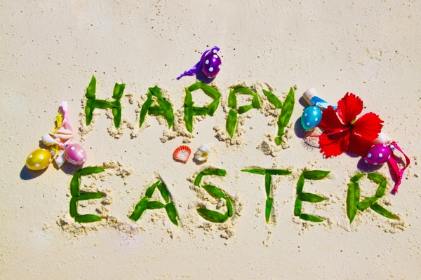 God påske skrevet i sand med prikkete egg og rød hibiskusblomst