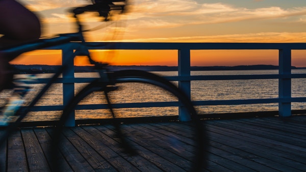 Uklart sykkel på en strandpromenade med solnedgang over Gdansk-bukta.