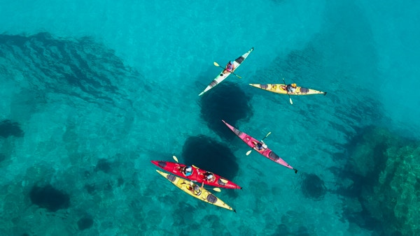 En gruppe turister i fargerike kajakker på det azurblå havet utenfor Kefalonia