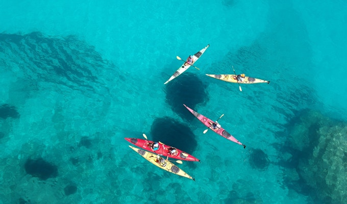 En gruppe turister i fargerike kajakker på det azurblå havet utenfor Kefalonia