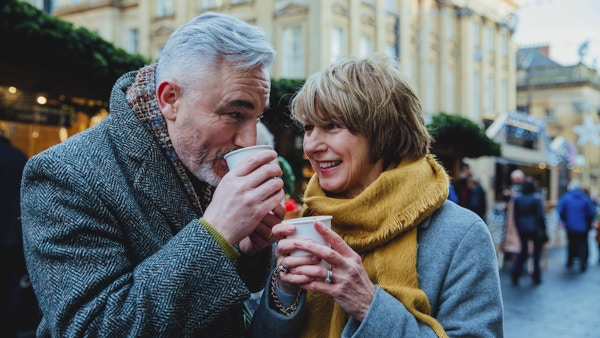Eldre par drikker varme drikker i et julemarked i byen.