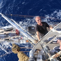 En mann som henger i masten på et skip