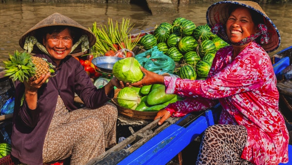 Vietnamesisk kvinne som selger frukt på det flytende markedet, Mekong River Delta, Vietnam