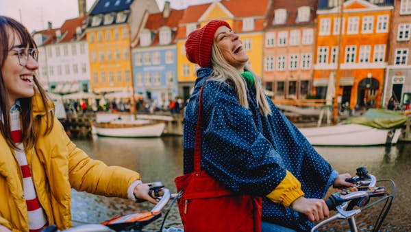 Bilde av to unge kvinner som sykler og har det gøy mens de oppdager den nye byen sammen.