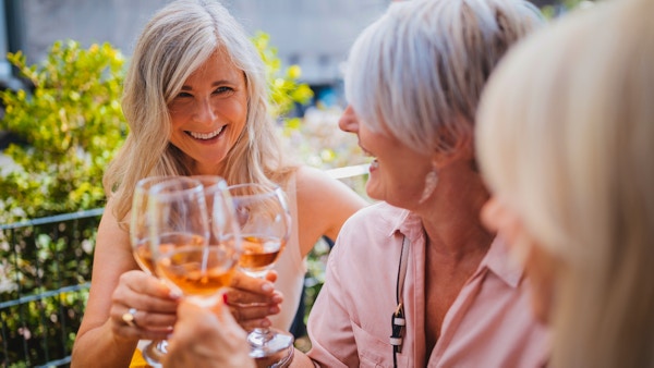 Fasjonable modne kvinner koser seg med å skåle og drikke vin på en luksuriøs restaurant i Frankrike