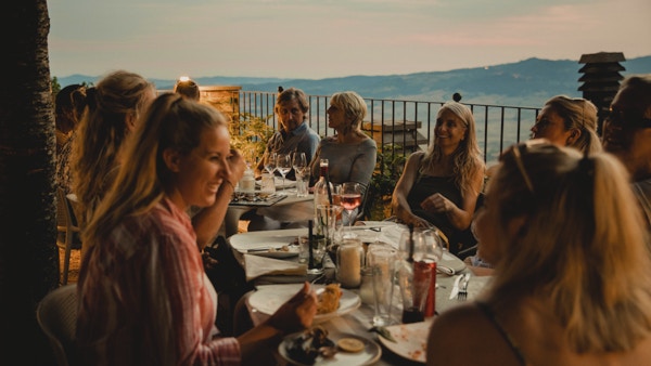 Stor gruppe mennesker som nyter et italiensk måltid sammen på toppen av en restaurant på taket.