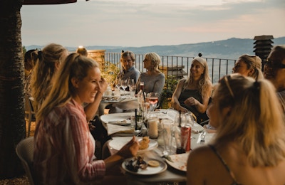 Stor gruppe mennesker som nyter et italiensk måltid sammen på toppen av en restaurant på taket.