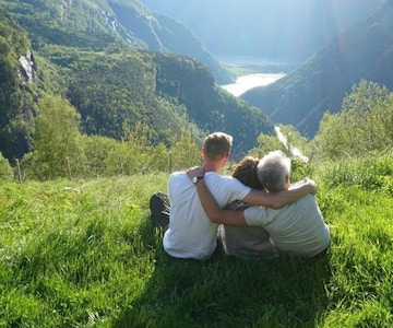 Tre personer nyter utsikten over fjell og fjord.