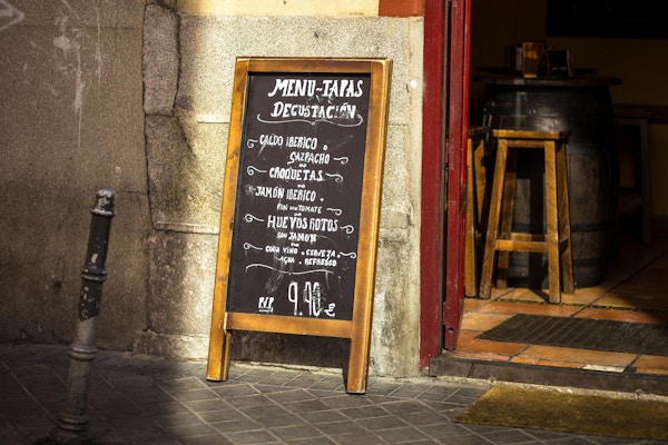 Et tavle utenfor en Madrid-restaurant tilbyr en smaksmeny med typiske tapasretter til en fast pris.