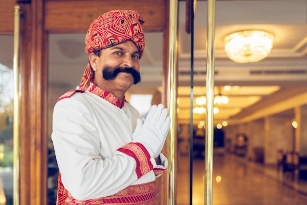 Indisk portner som ønsker gjester velkommen ved en hotellinngang i Agra, India