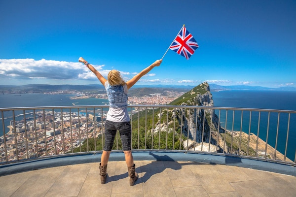 Kvinne med det britiske flagget i hånden på toppen av Gibraltar Rock. Gibraltar er et territorium i Sør-Vest-Europa som er en del av Storbritannia.