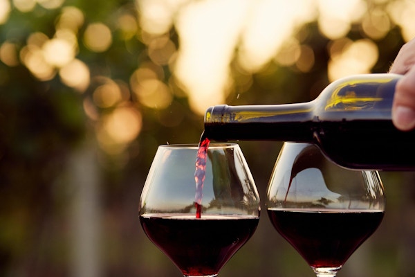 To rødvinsglass som fylles opp på en vingård