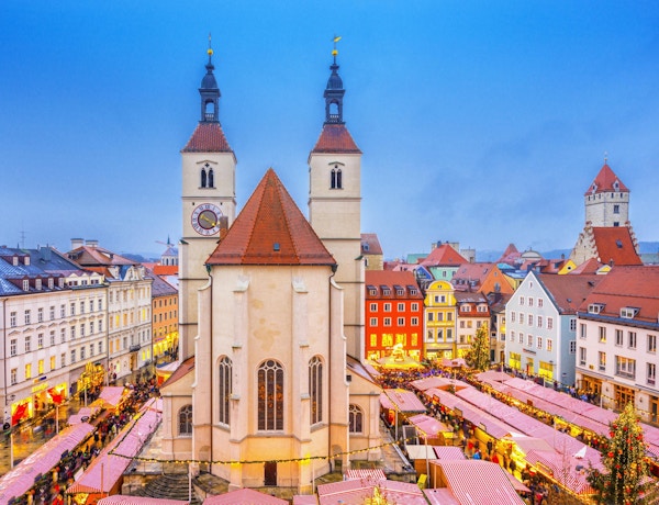 Forhøyet utsikt over Regensburgs julemarked med mat og julepyntboder rundt den 500 år gamle Neupfarr-kirken og vakre byhus.