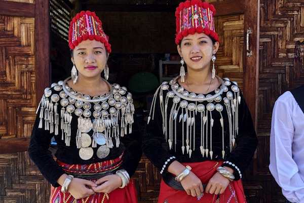 To lokale damer i tradisjonelle kostymer med sølv og røde farger. Foto.