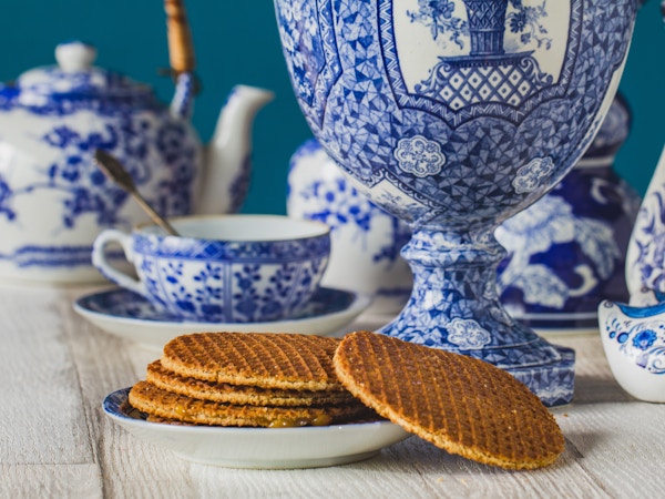 Tradisjonell nederlandsk stroopwafel med sirup, informasjonskapsel og te, Delfts blå dekorativ servise satt på bordet, nærbilde, makrofoto