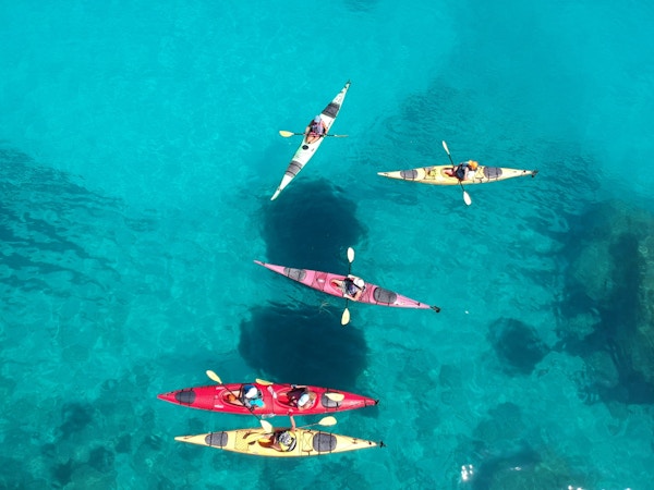 En gruppe turister som padler i fargerike kajakker på det asurblå havet