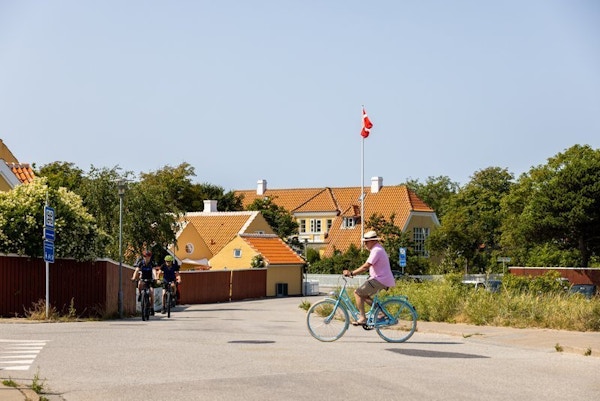 Syklister i småby med gule hus.