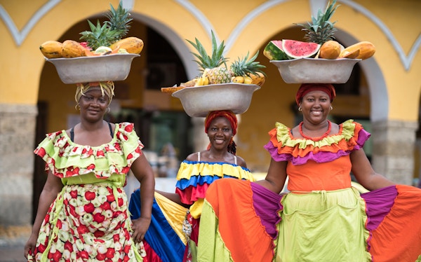 Glade kvinner som selger frukt i Cartagena og ser smilende på kameraet - å reise som en lokal