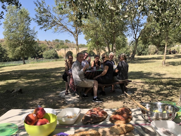 mennesker rundt et bord som koser seg med god mat og drikke fra et piknikkbord