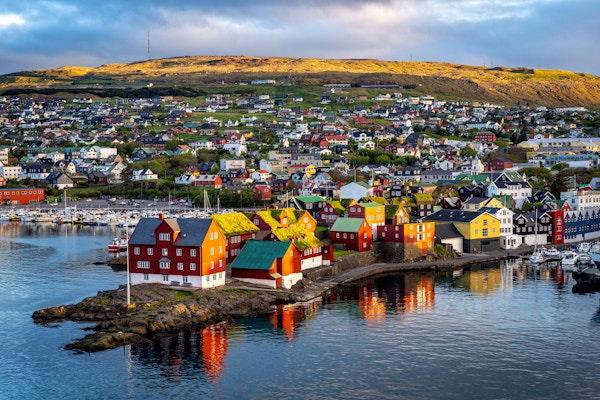 Soloppgangsscene i hovedstaden Torshavn på Færøyene i Nord-Atlanteren. Urban scene av skandinavisk by i varmt gyllent sollys.