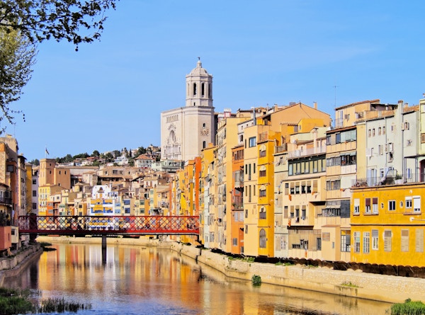 Fargerike hus i Girona som reflekterer i Onyar-elven.