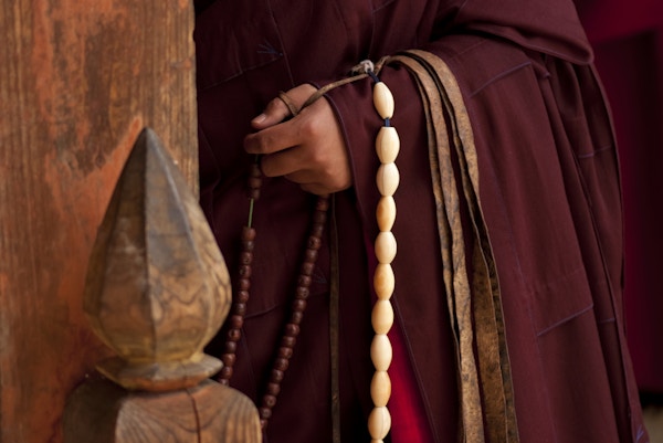 En buddhistisk munk i et kloster i landlige Bhutan draperer et stykke elfenbensbønnekuler fra hans utstrakte arm. Etterspørselen etter elfenben i religiøse kretser i hele Asia har eskalert ulovlig handel de siste årene og truet ville elefantbestander.