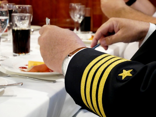 Nærbilde av kapteinens hender som spiser i restauranten