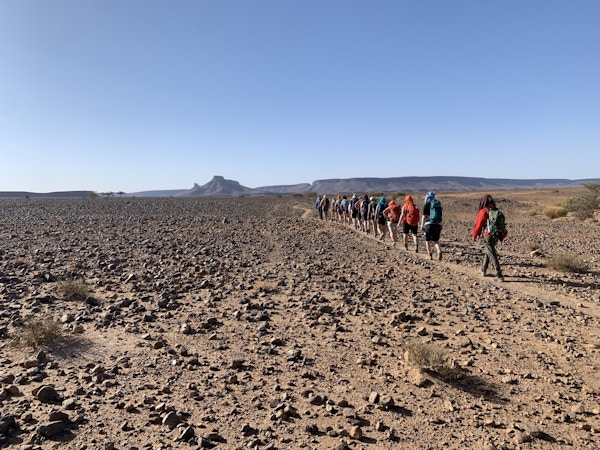 Gruppe turgåere på rekke innover ørkenen mot Bani fjellene