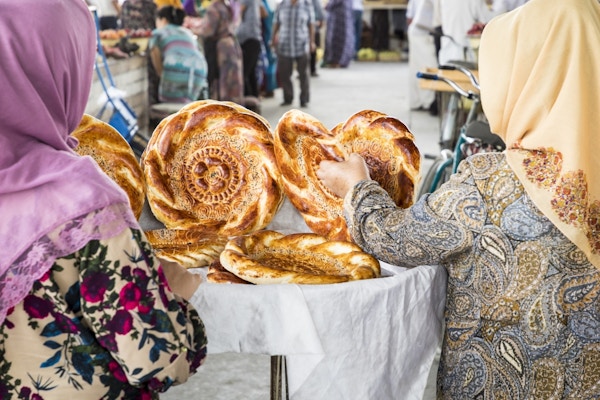 To kvinner fotografert bakfra med tradisjonell usbekisk brødlavash på lokal basar, er et mykt flatbrød fra Midt-Asia (Usbekistan).