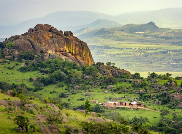 Ezulwini-dalen i Swaziland Eswantini med vakre fjell, trær og steiner i en naturskjønn grønn dal mellom Mbabane og Manzini byer. Tradisjonelle hytter i Swaziland