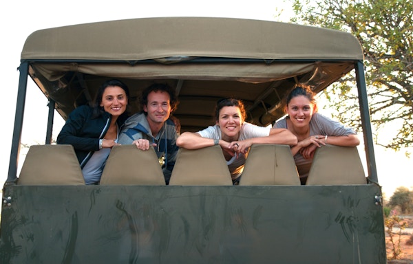 Fire glade smilende venner etter en vellykket dag med safari i Kruger-parken ved solnedgang