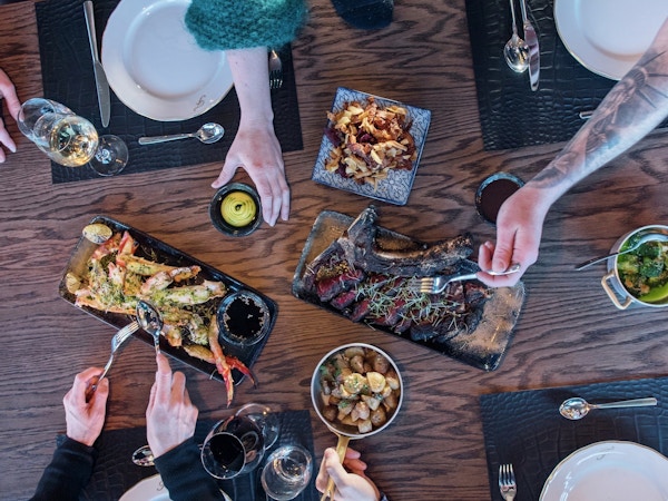 Fem matfatpå bordet der flere forsyner seg med mat på det dekkede bordet