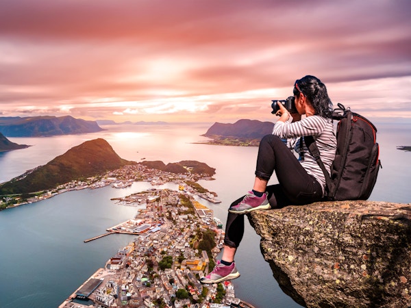 Naturfotograf turist med kameraskudd mens han står på toppen av fjellet. Aksla i byen Ålesund, Norge.